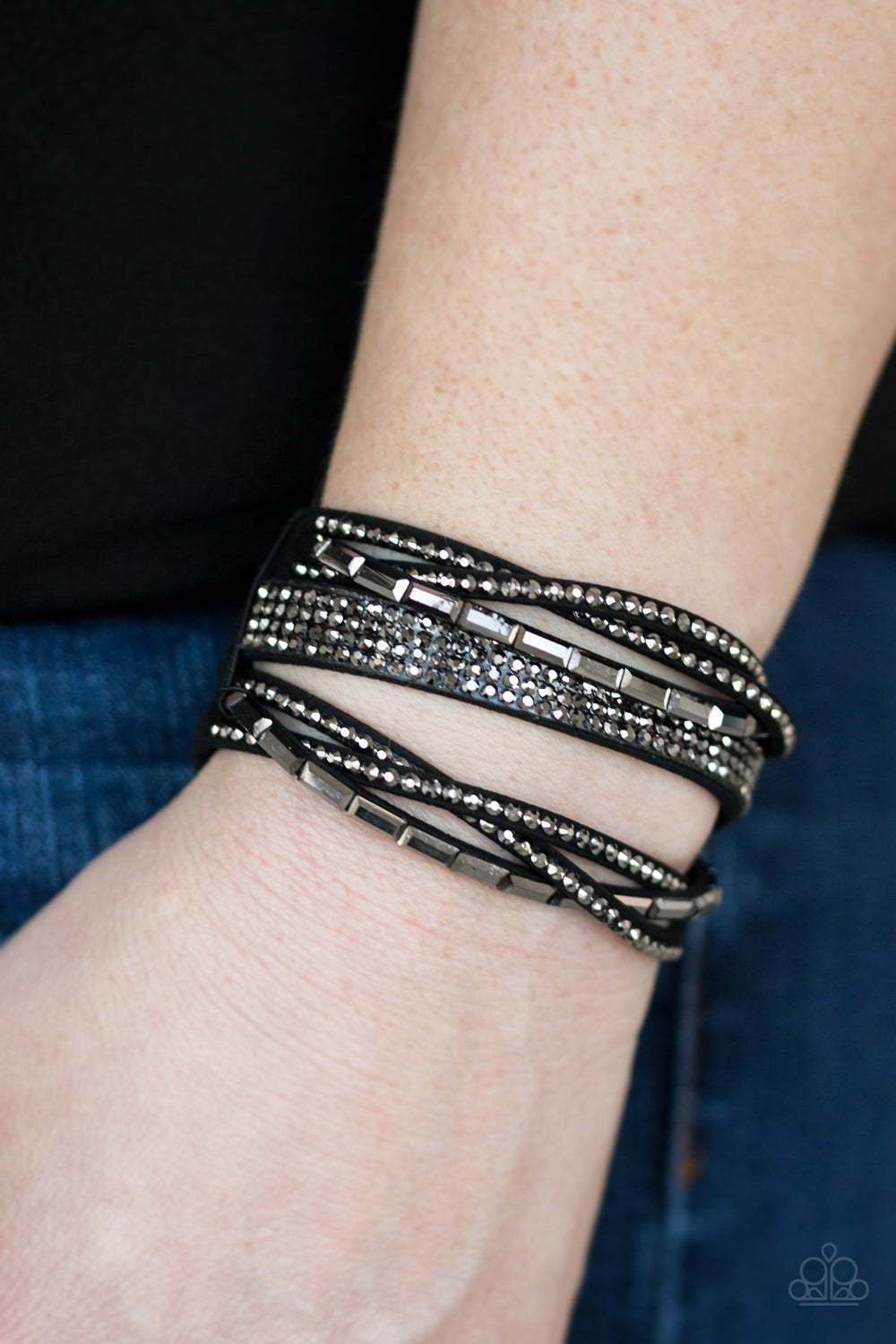 Featuring edgy emerald and classic style cuts, glittery hematite rhinestones are encrusted along crisscrossing strands of black suede