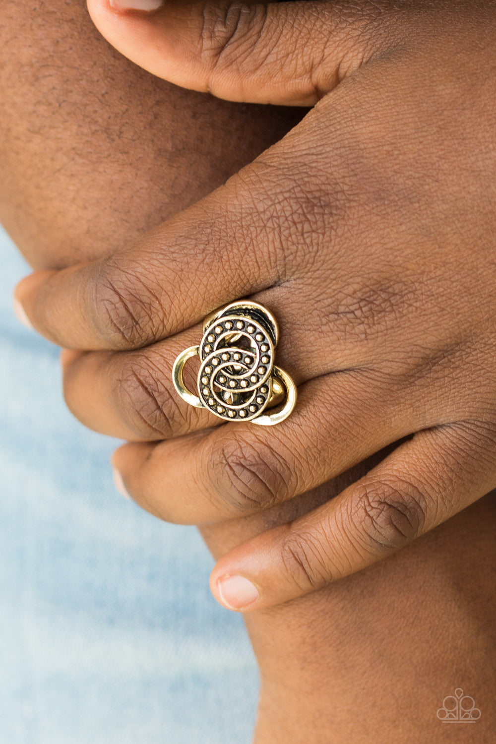 Dotted in shimmery brass studs, antiqued rings sit atop a dizzying brass backdrop for an edgy geometric look.