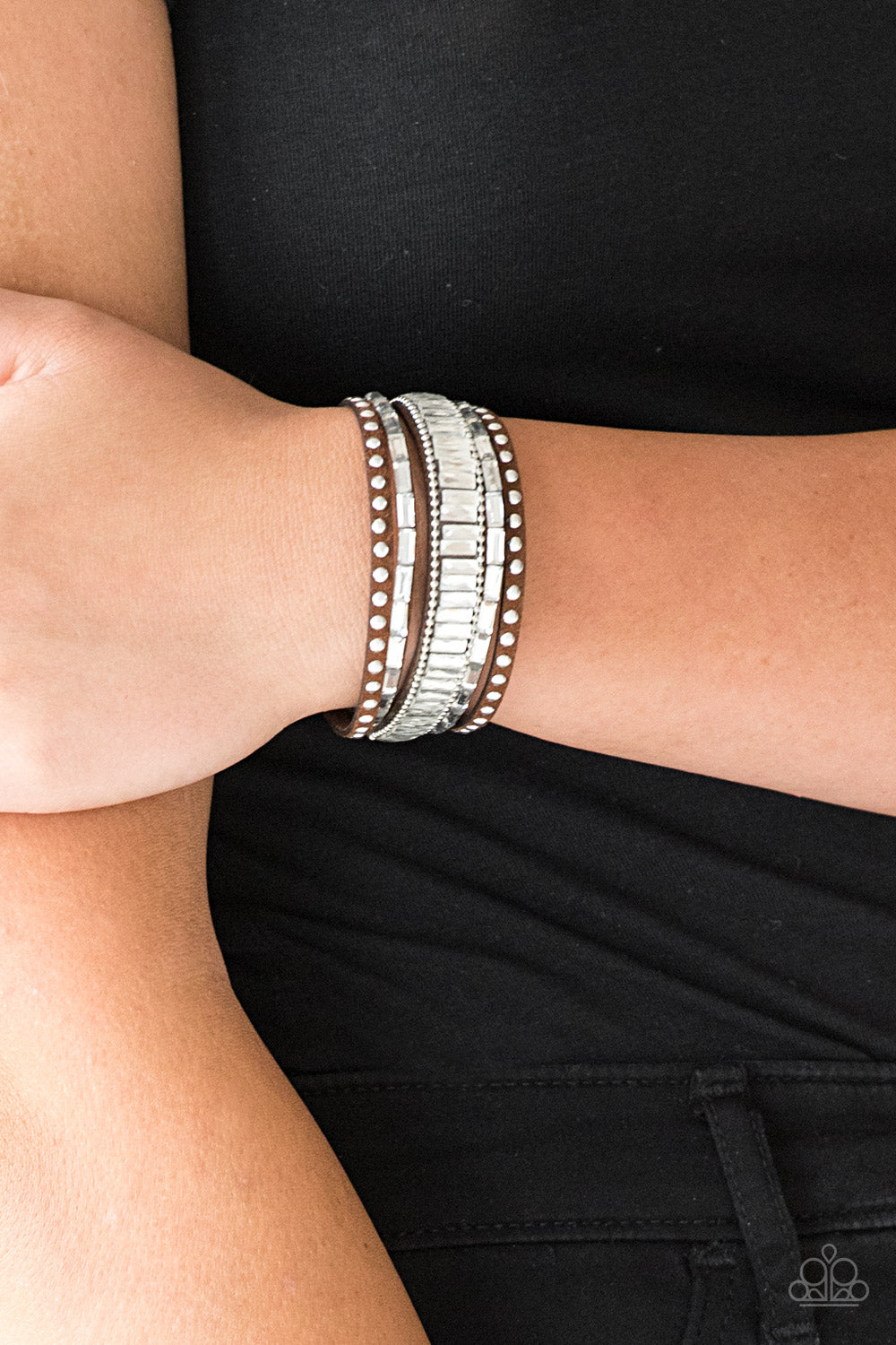 Shiny silver studs, dainty silver ball chains, and edgy white emerald-cut rhinestones race along a spliced brown suede band for a rock star look.