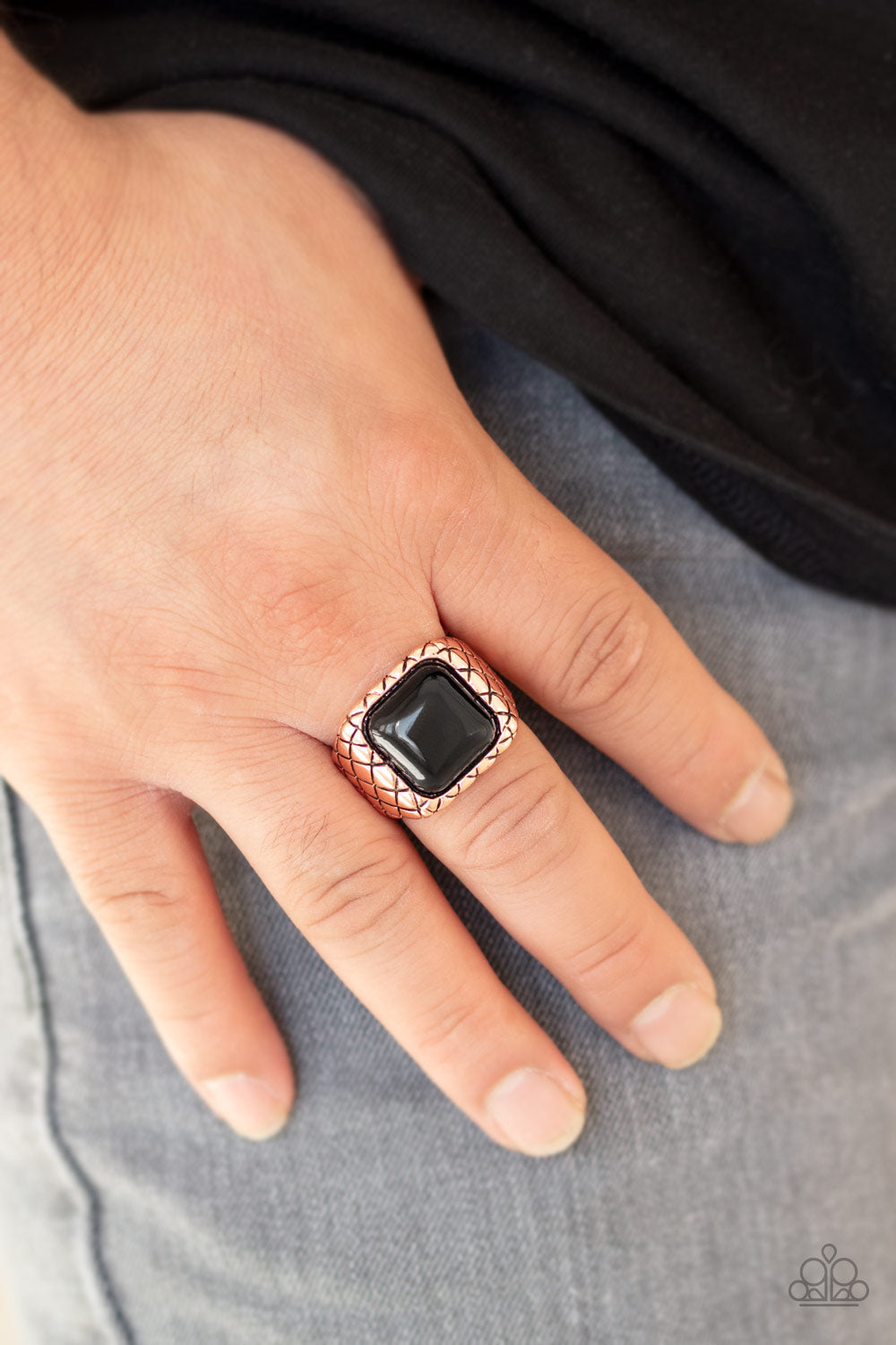 An oversized black square bead is pressed into the center of a thick copper band stamped in crisscrossing texture 