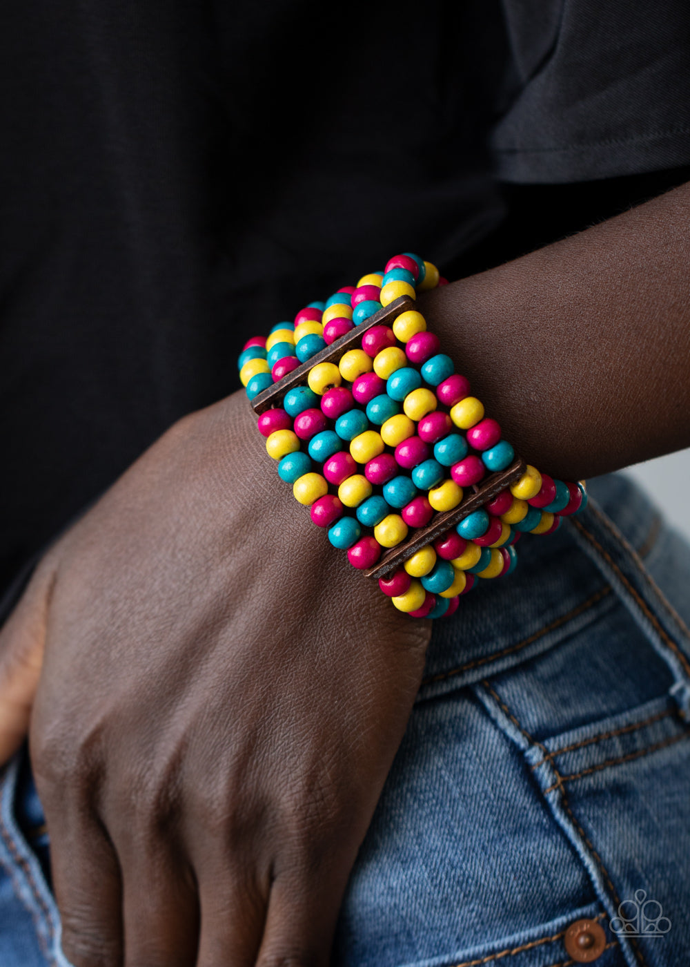 Held together with rectangular wooden fittings, strands of vivacious pink, yellow, and blue wooden beads are threaded along stretchy bands 