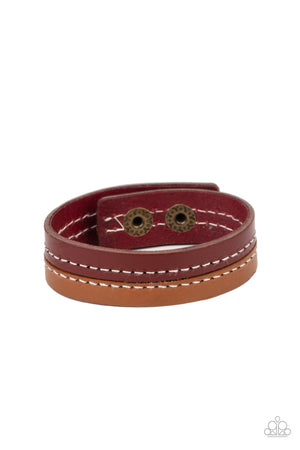 Strands of tan and red leather are stitched together, creating a rugged display around the wrist