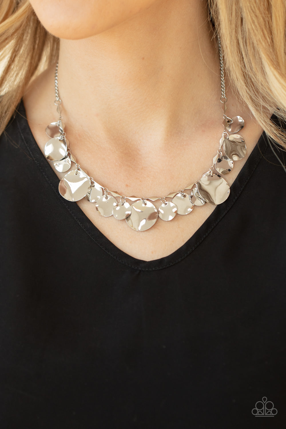 Featuring diamond shaped silver fittings, a mismatched collection of hammered silver discs swings from a classic silver chain