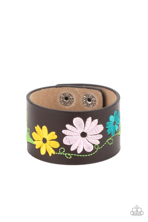 loral pattern is embroidered across the front of a brown leather band