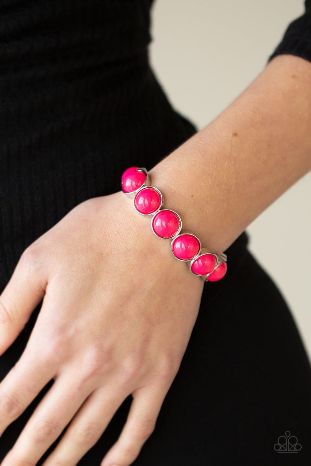 Featuring flamboyant pink beaded centers, bubbly silver frames are threaded along stretchy bands around the wrist for a powerful pop of color.