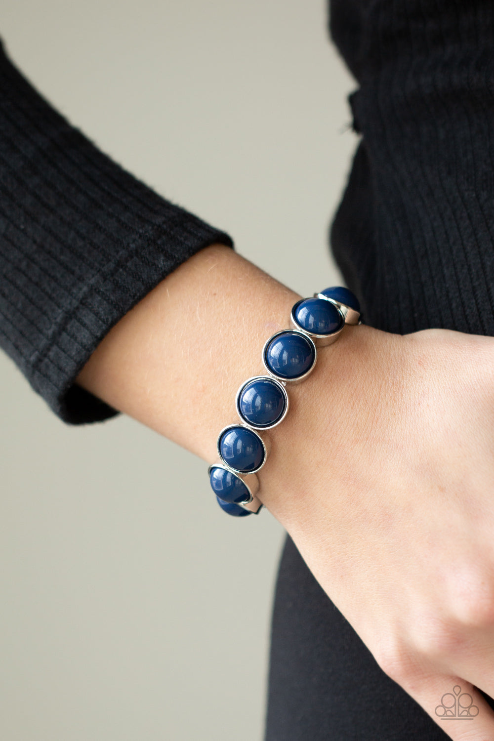 Featuring depthless blue beaded centers, bubbly silver frames are threaded along stretchy bands around the wrist for a powerful pop of color.