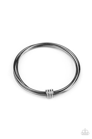 A white rhinestone encrusted fitting glides along a trio of gunmetal bangles, creating a solitaire bracelet around the wrist.