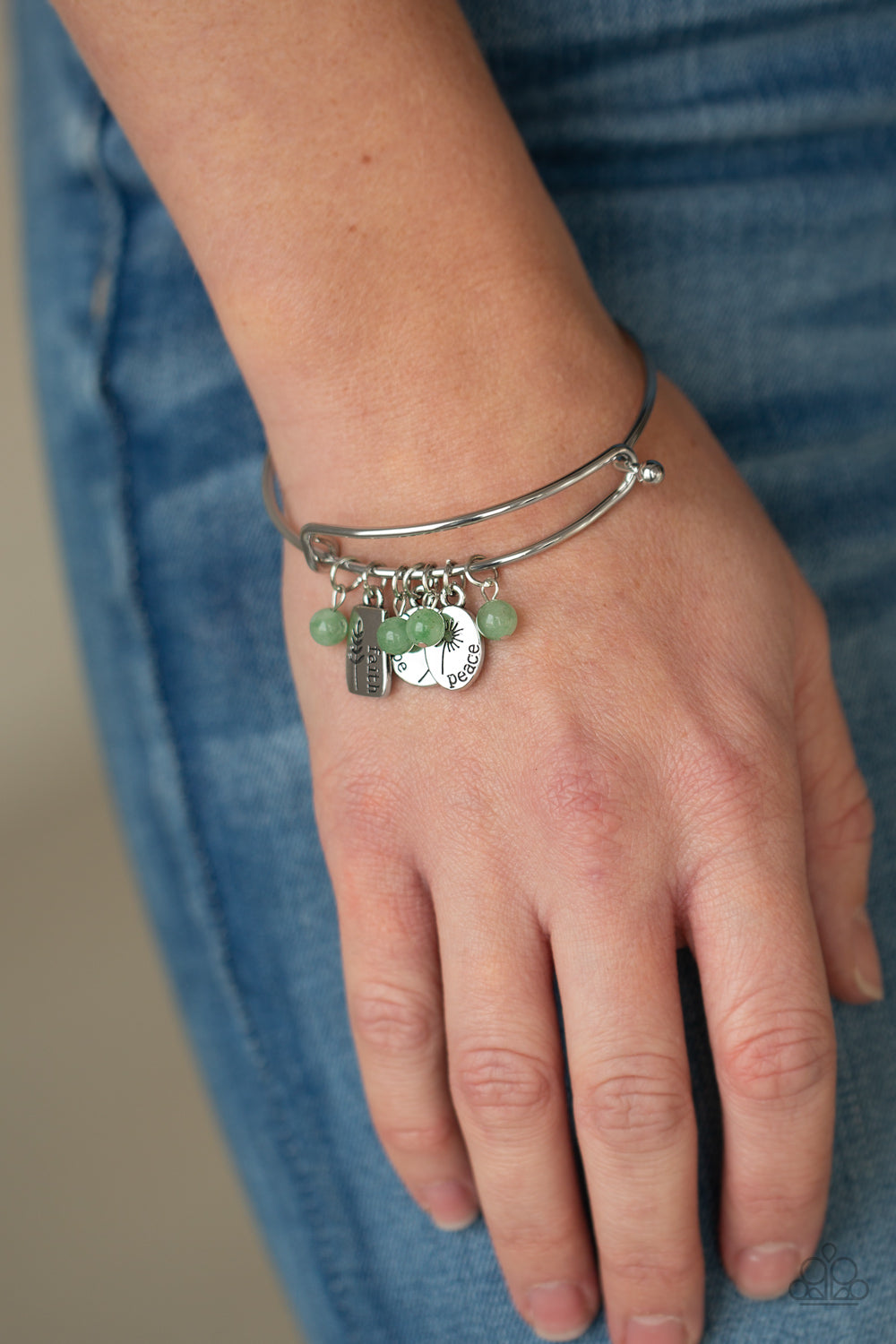 Glassy green stone beads and silver floral charms stamped in the words, "faith," "hope," and "peace," glide along a dainty bangle-like cuff