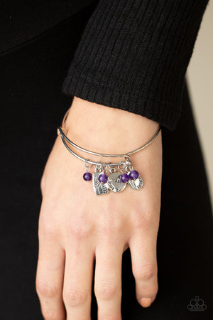 Glassy purple stone beads and silver floral charms stamped in the words, "faith," "hope," and "peace," glide along a dainty bangle-like cuff