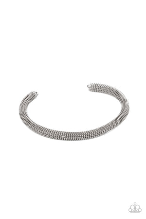 A dainty row of glistening silver chain twists around a silver cuff, creating an edgy industrial display around the wrist.