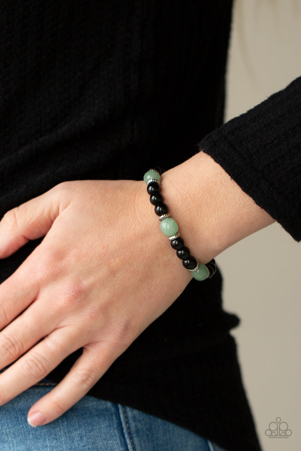 Infused with dainty silver accents, glassy black and green stone beads are threaded along a stretchy band around the wrist for a stackable seasonal look.