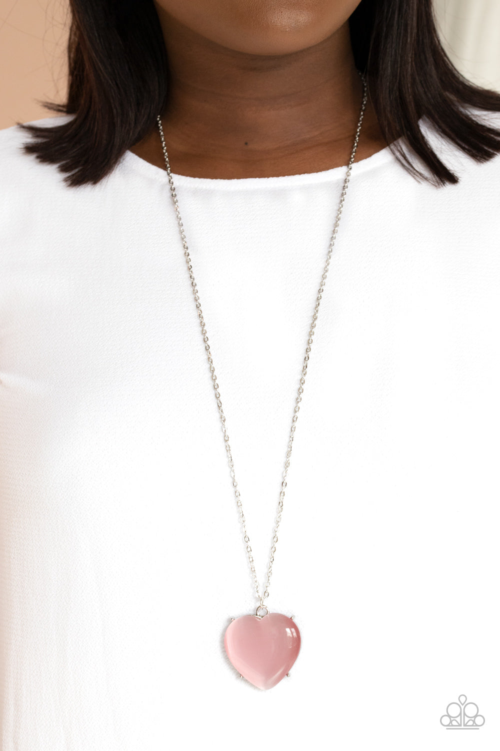 oversized pink cat's eye stone frame swings from the bottom of a lengthened silver chain