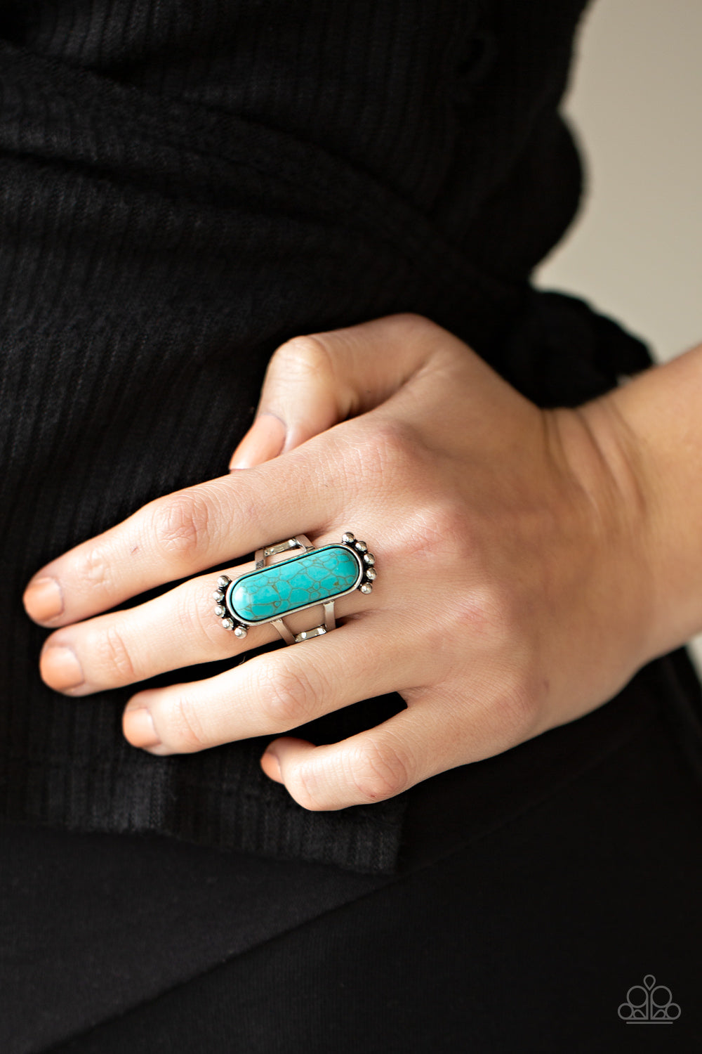 oblong turquoise stone is pressed into a sleek silver frame featuring a studded top and bottom