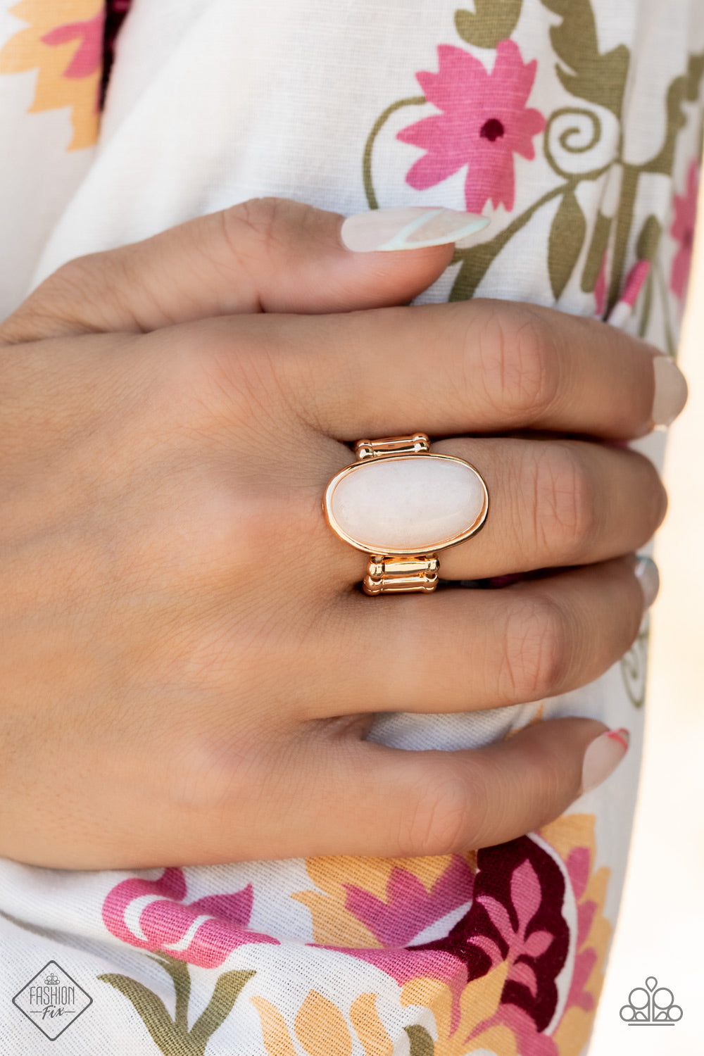 A white oval stone is encased inside a sleek gold frame, creating a mystical centerpiece atop the finger.