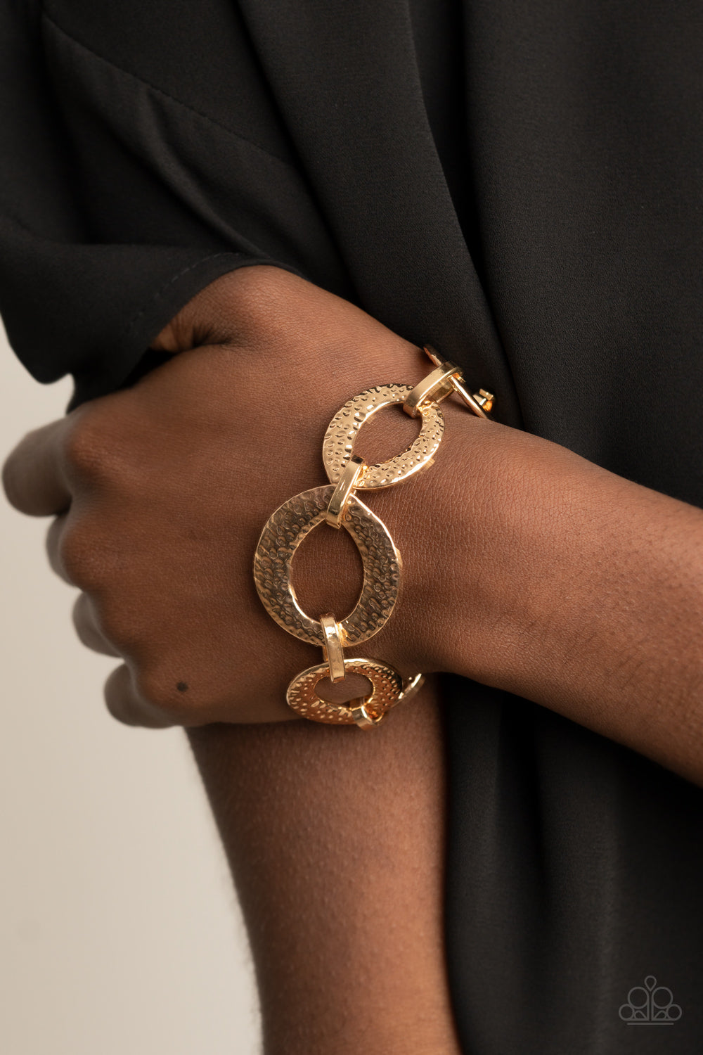 Asymmetrical gold links and hammered oval frames delicately connect around the wrist