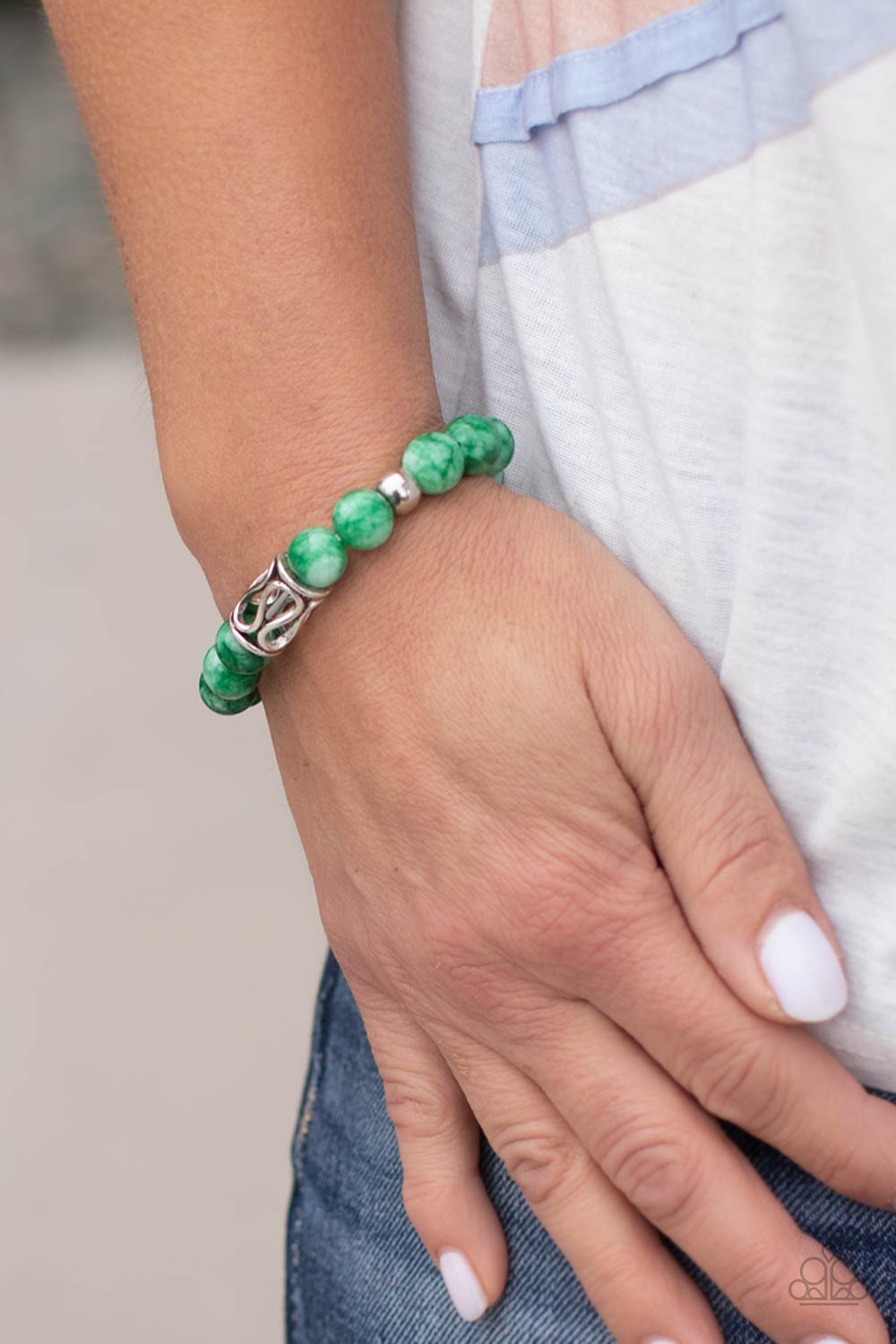 Infused with an ornate silver centerpiece, an earthy collection of silver and jade beads are threaded along a stretchy band around the wrist for a seasonal flair.