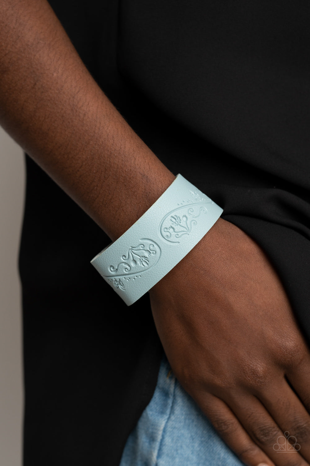 Cerulean leather band is stamped in a decorative butterfly and flower pattern