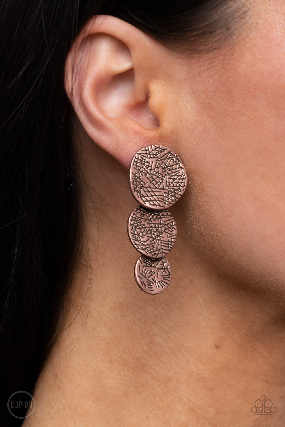 Scratched in a tactile pattern, warped copper discs decrease in size as they overlap into a rustic lure