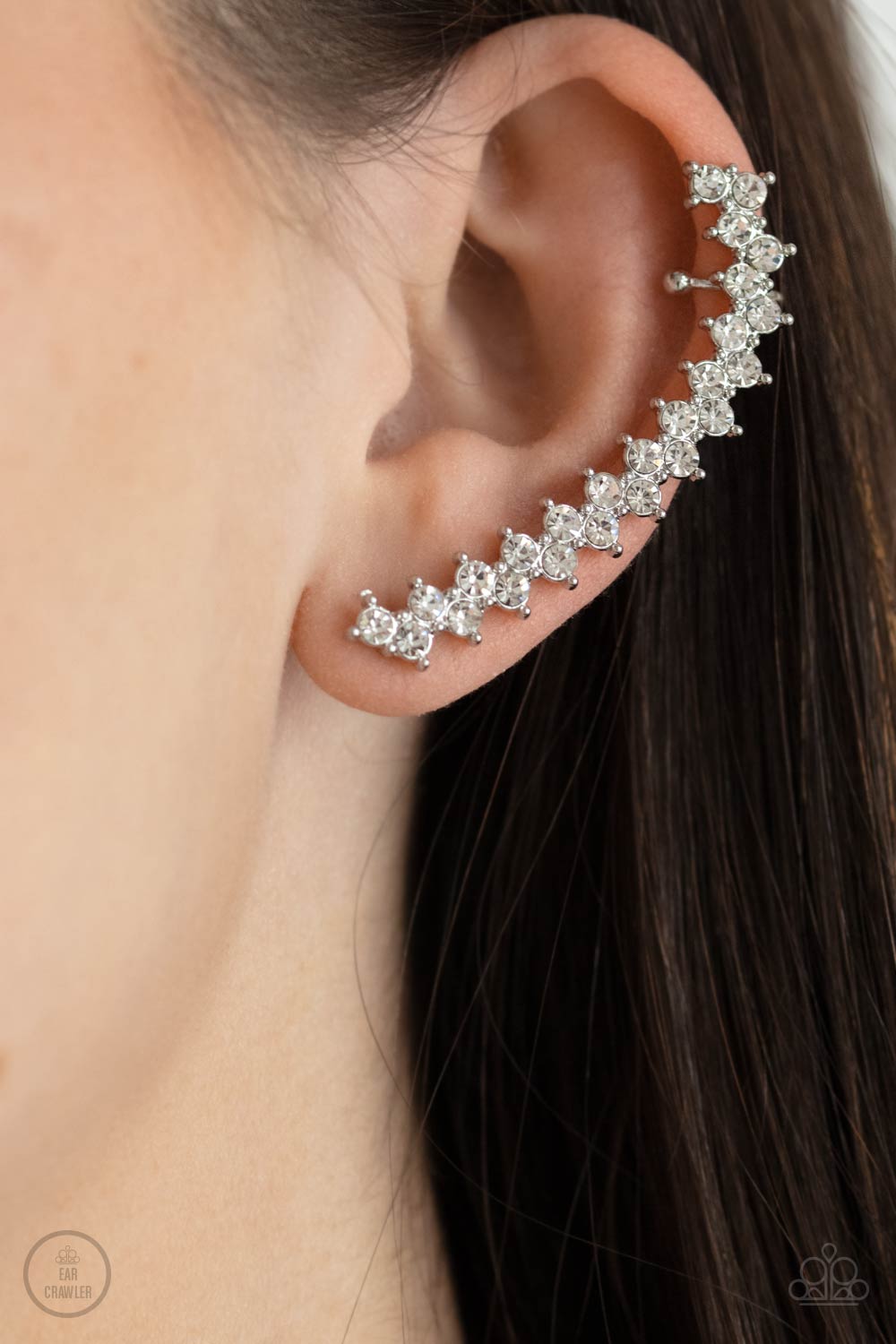 Encased in studded silver fittings, pairs of glassy white rhinestones stack into a zigzagging frame up the ear 