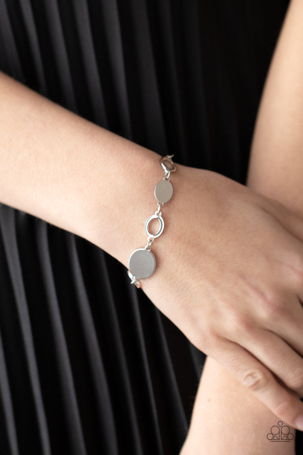 shiny series of glistening silver discs and oval frames delicately link around the wrist
