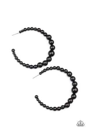 Gradually increasing in size at the center, a classic row of polished black beads are threaded along an oversized hoop for a posh finish