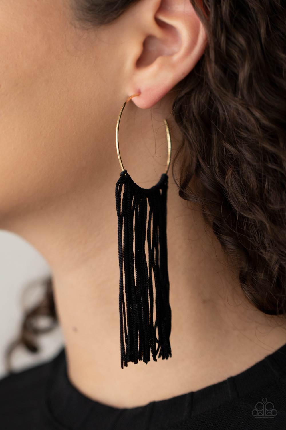 black cords stream from the center of a dainty gold hoop, creating a glamorous fringe