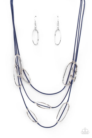 An asymmetrical collection of hammered silver ovals are fitted in place along three rows of shiny blue cords