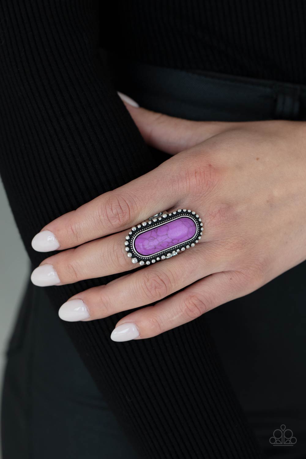 oblong purple stone is nestled inside an oversized studded silver frame