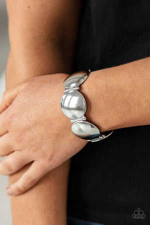 Infused with curved bar-like accents, a shiny series of beveled silver discs are threaded along stretchy bands