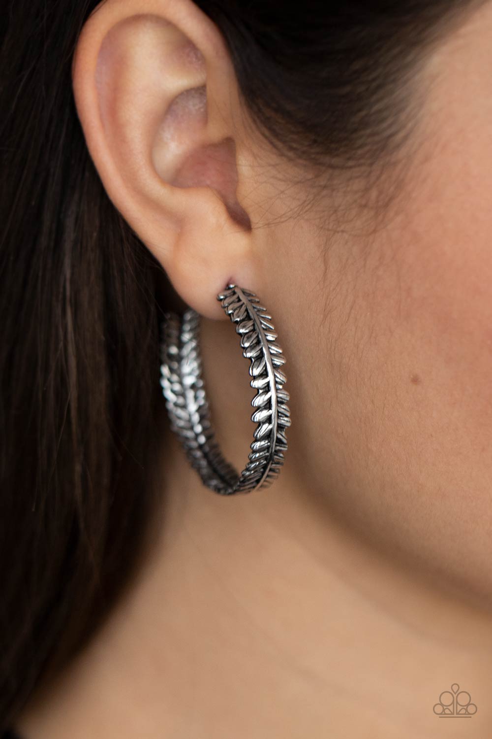 antiqued shimmer, a leafy silver frame delicately curls into a whimsical hoop.