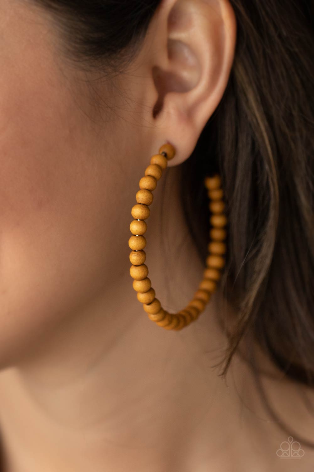Brown wooden beads are threaded along a dainty wire, creating an earthy hoop.