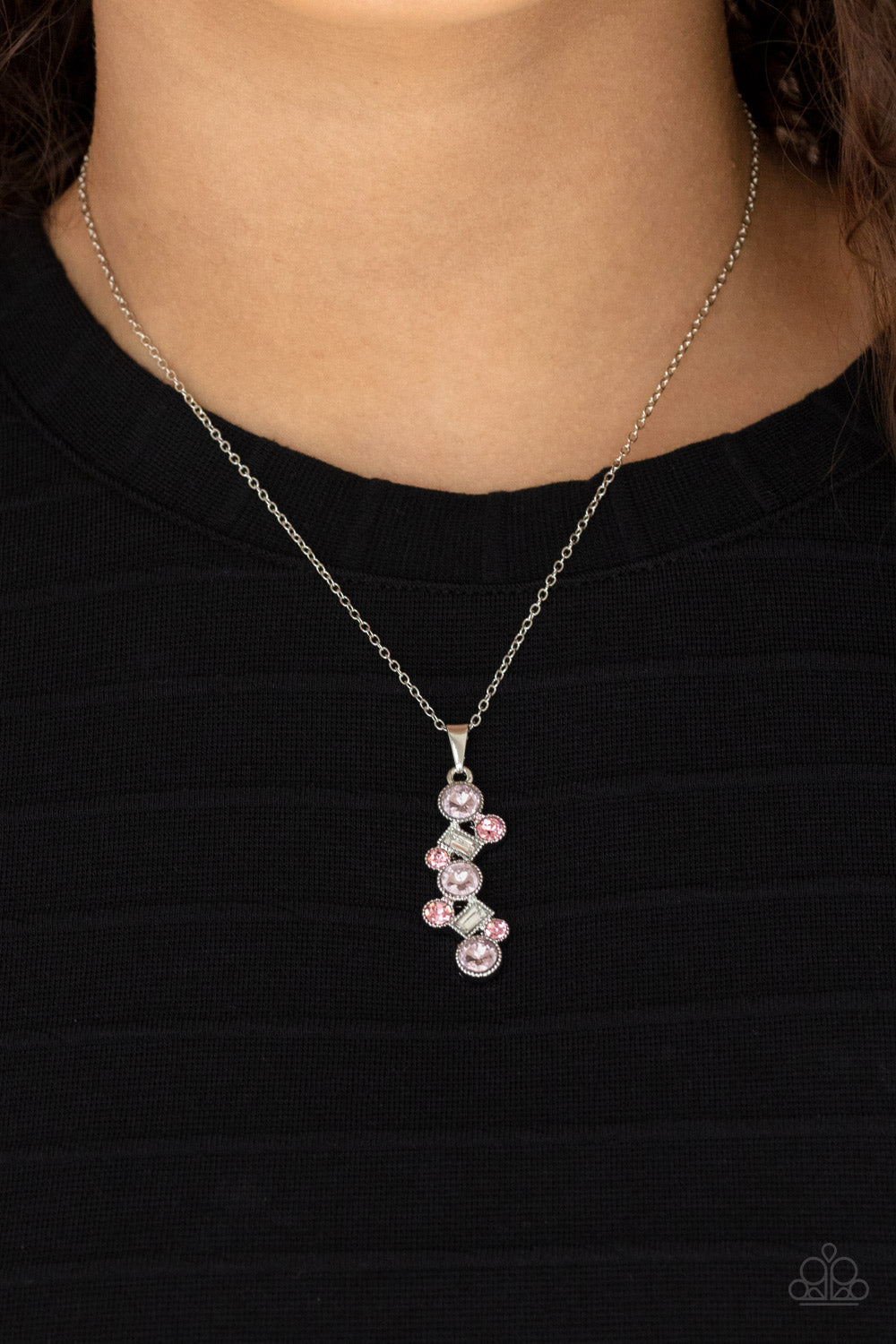 Featuring classic round and regal emerald style cuts, a glittery collection of pink and white rhinestones delicately coalesce into a glamorous pendant below the collar. 