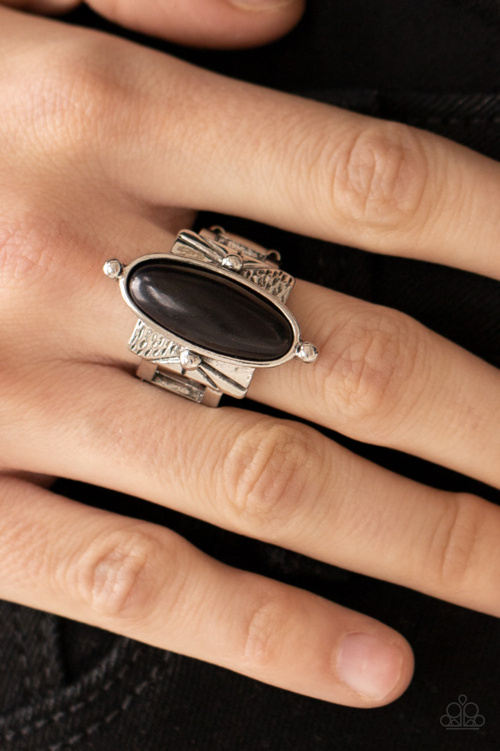 oval black stone is nestled inside a studded silver fitting that sits atop a decorative silver frame stamped in tribal inspired textures