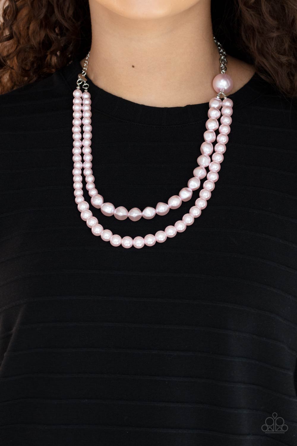 A dramatically oversized pink pearl gives way to two mismatched strands of classic pink pearls