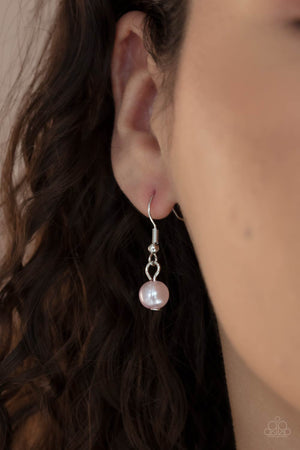 A dramatically oversized pink pearl gives way to two mismatched strands of classic pink pearls