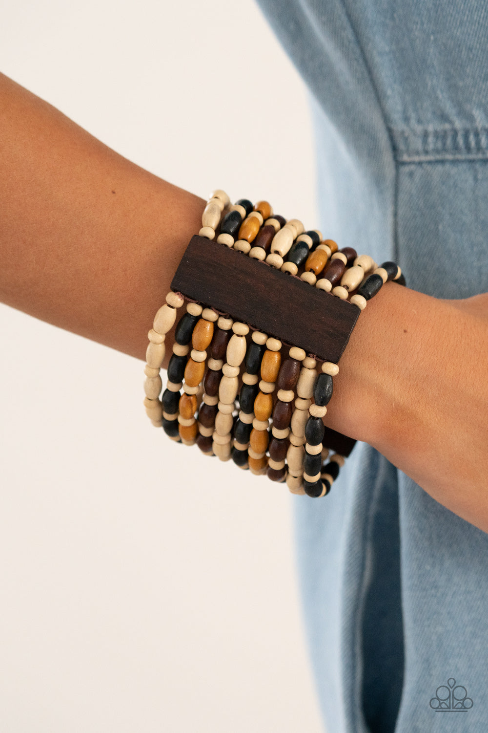 Held together with rectangular wooden frames, an earthy collection of white wooden beads and black, brown, and tan oval wooden beads