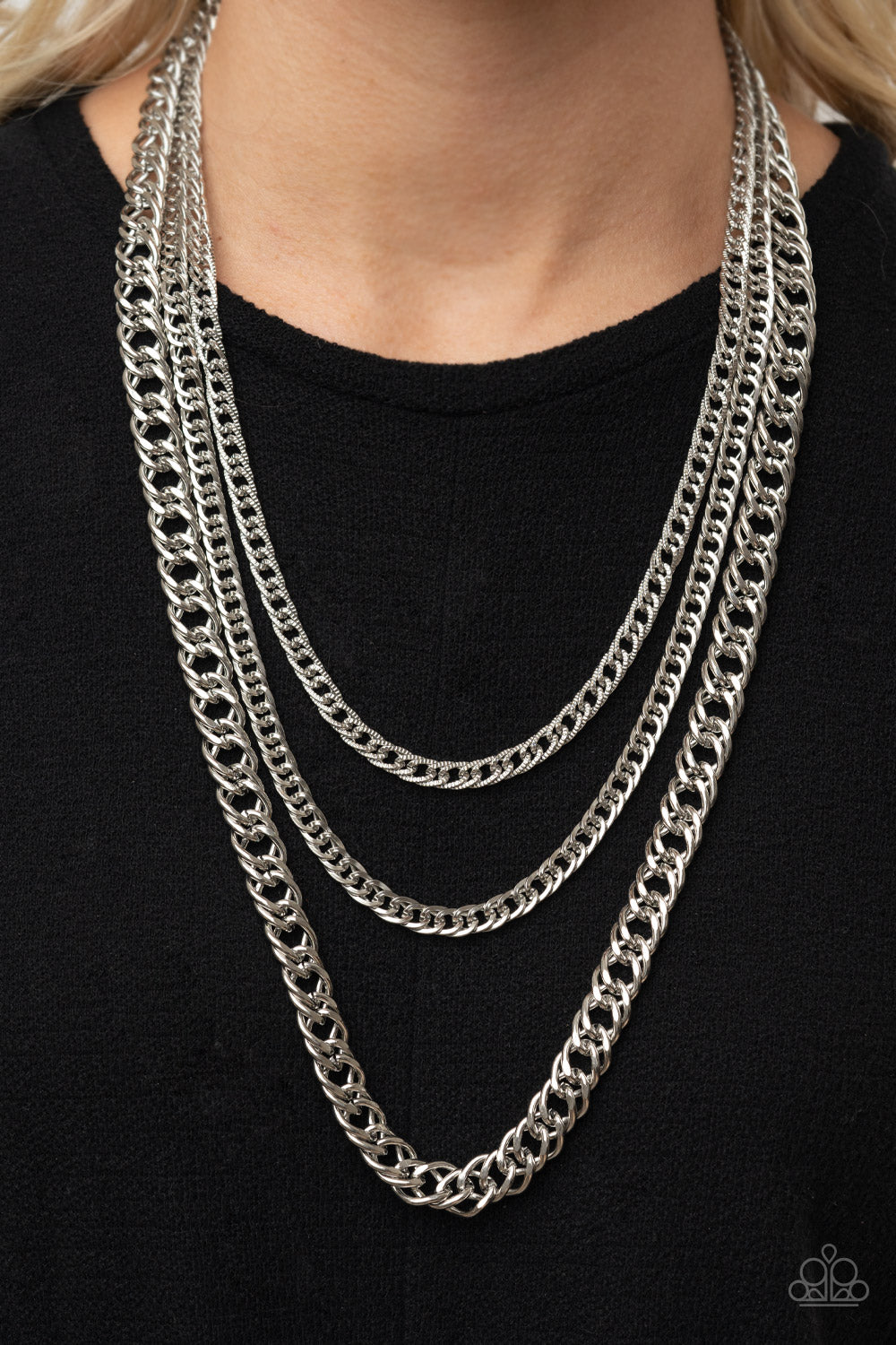 Bold layers of glistening silver chains of varying sizes and textures, fall like a weighty medal across the chest creating an edgy industrial effect.