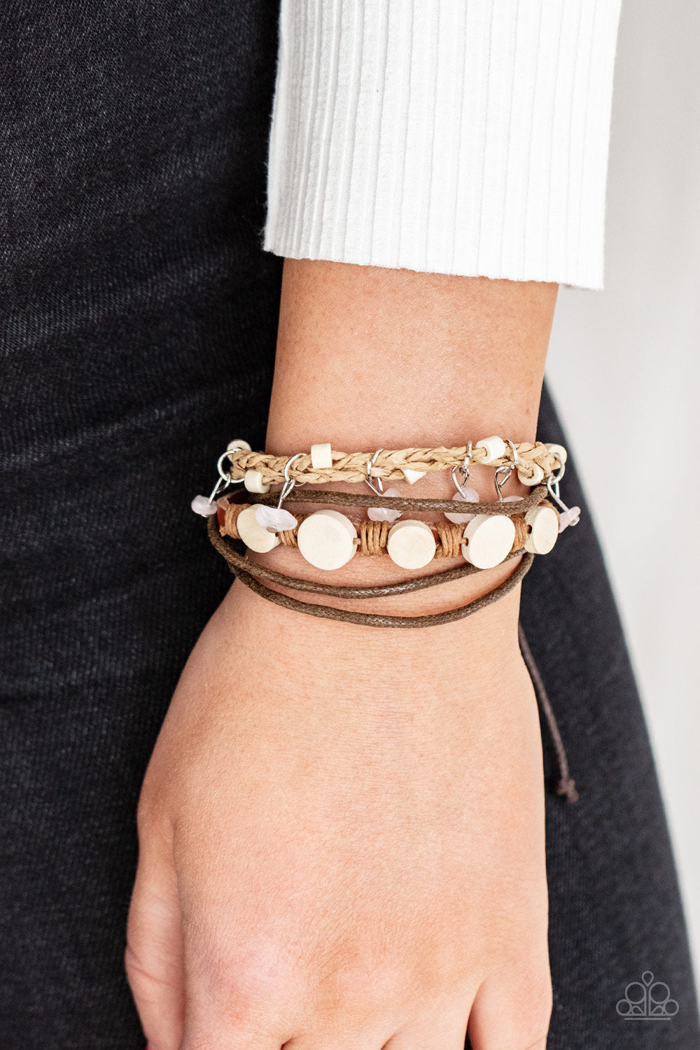 Assorted strands of cording and leather, featuring flat wooden beads and small pink polished stones dangling from silver fittings