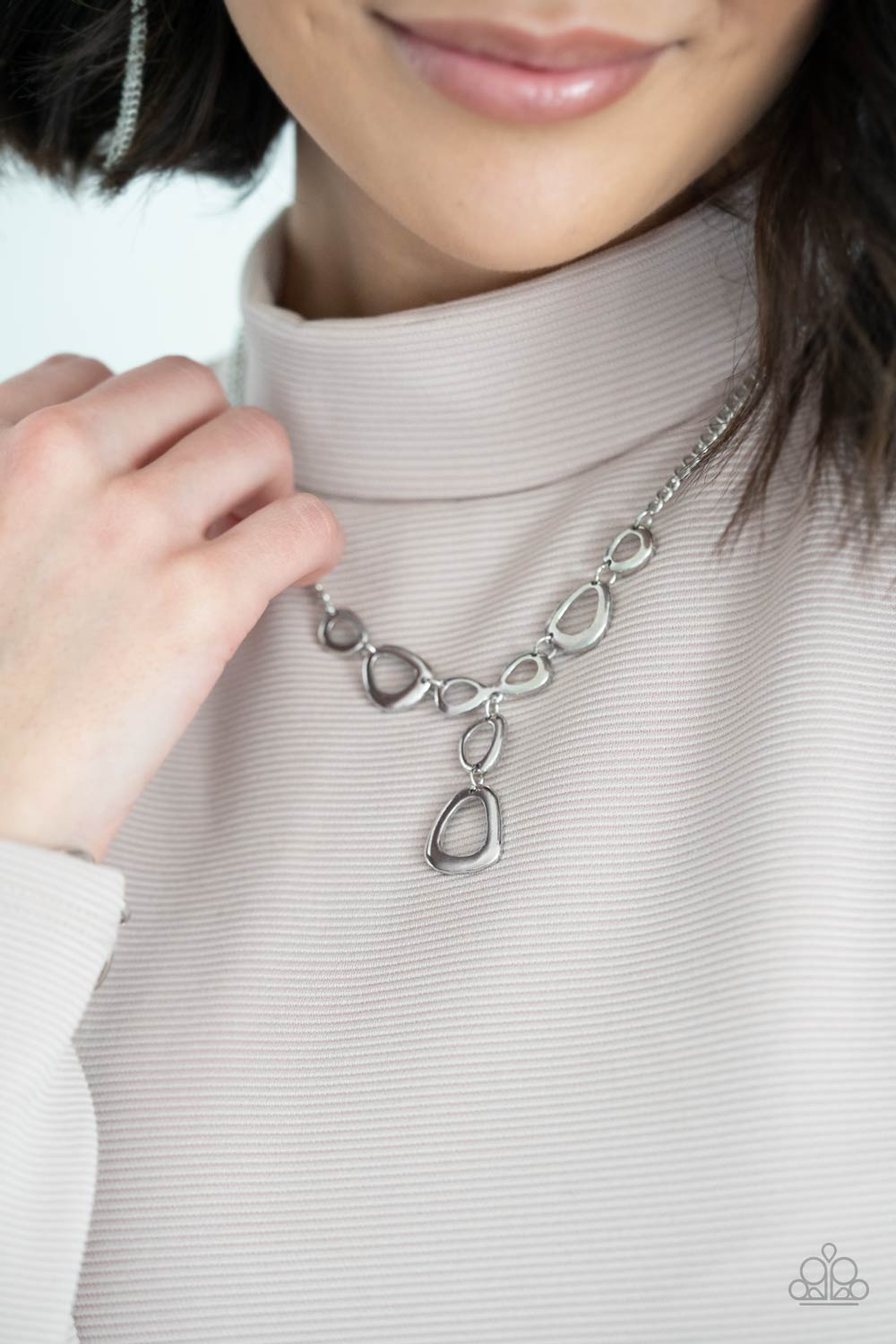 Irregular shaped silver rings connect to a sliver chain 