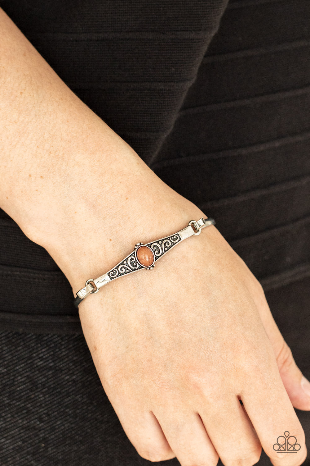 oval brown stone, an antiqued silver frame is embossed with a vine-like scroll that hooks to a dainty cuff-like bangle,