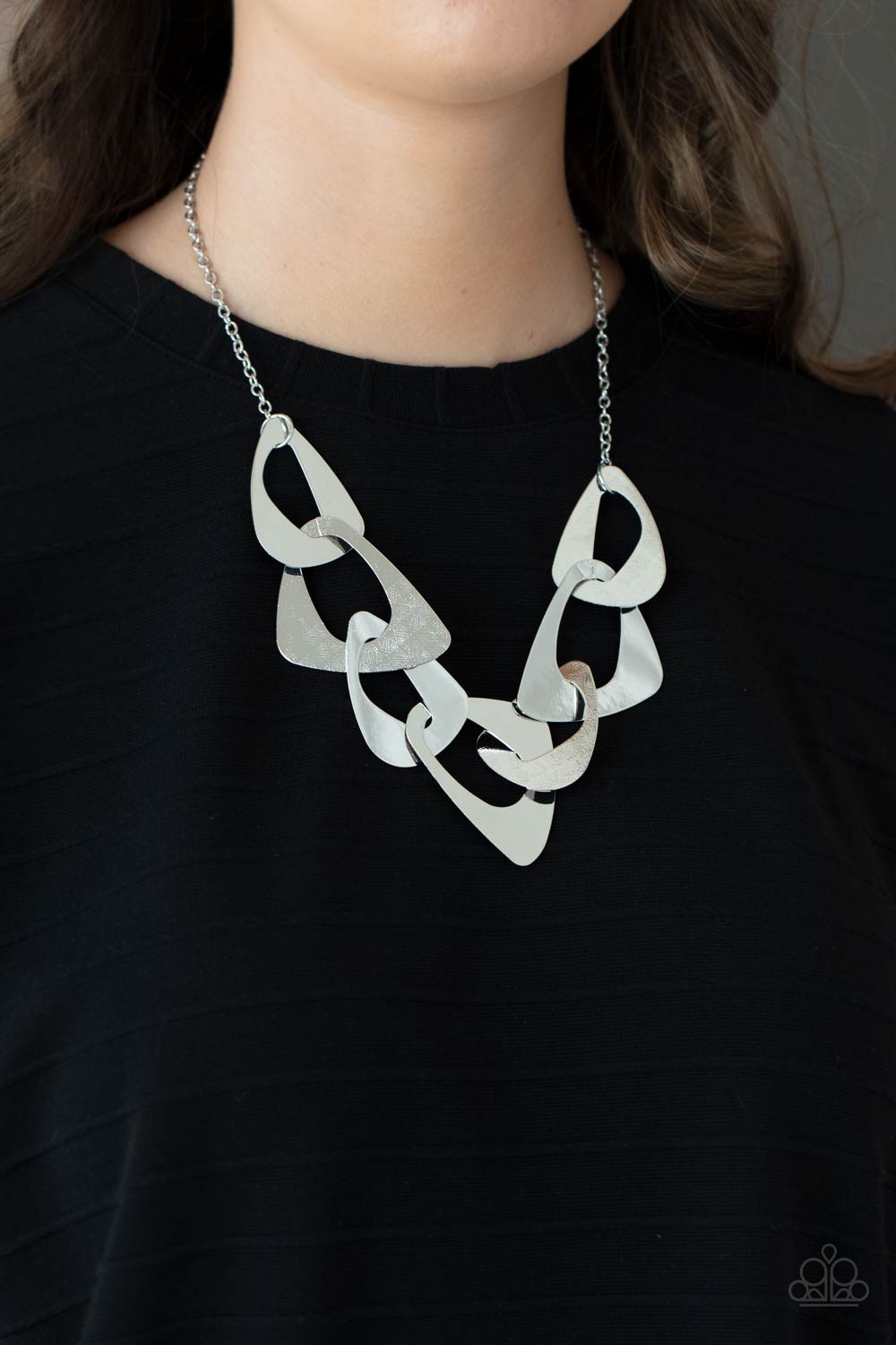 Large triangular cutouts stamped in a lightly dotted texture link below the collar forming a dramatic display of silver slices