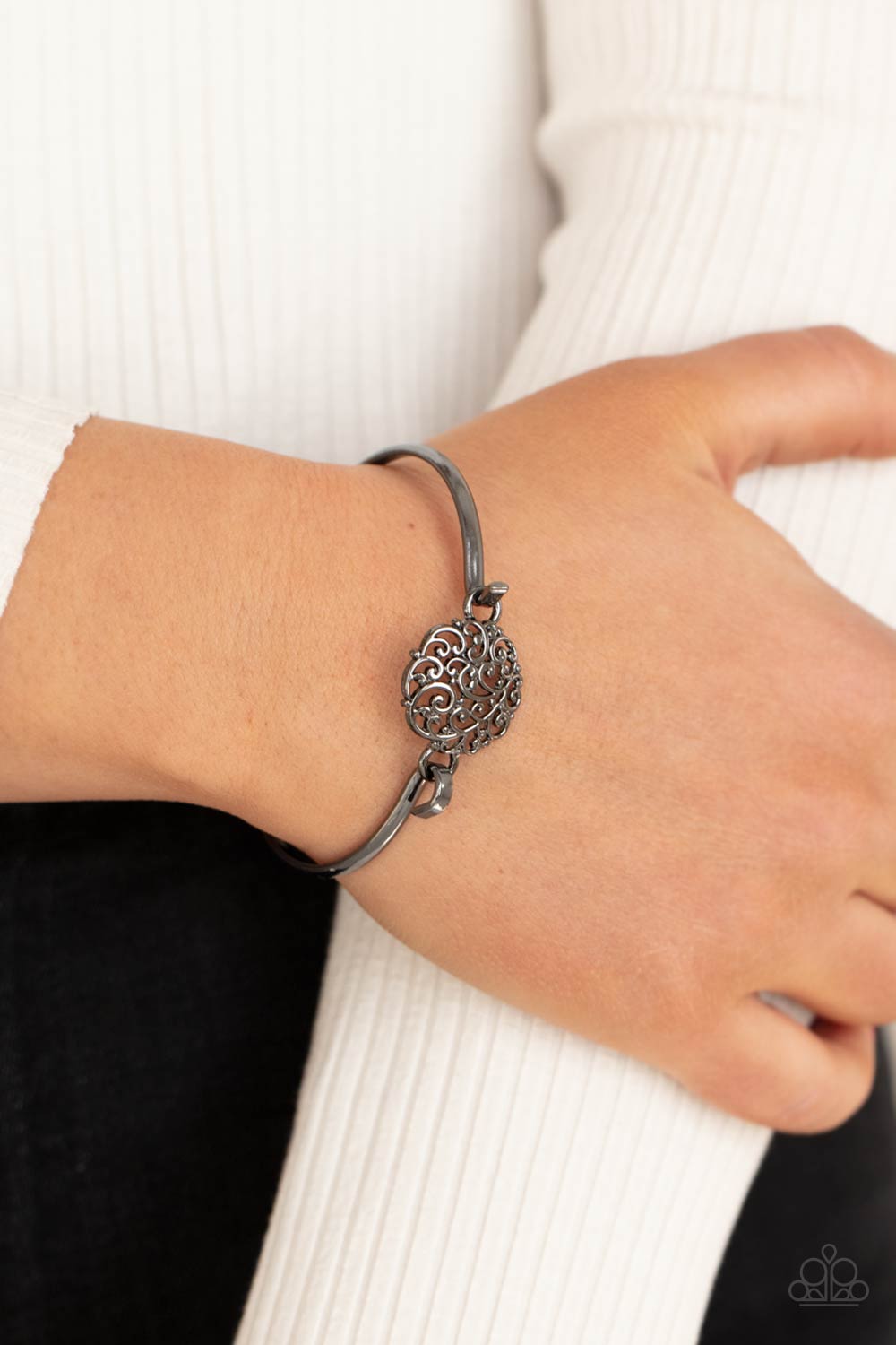 Shiny gunmetal filigree swirls into a round frame that hooks to a dainty gunmetal bangle-like cuff