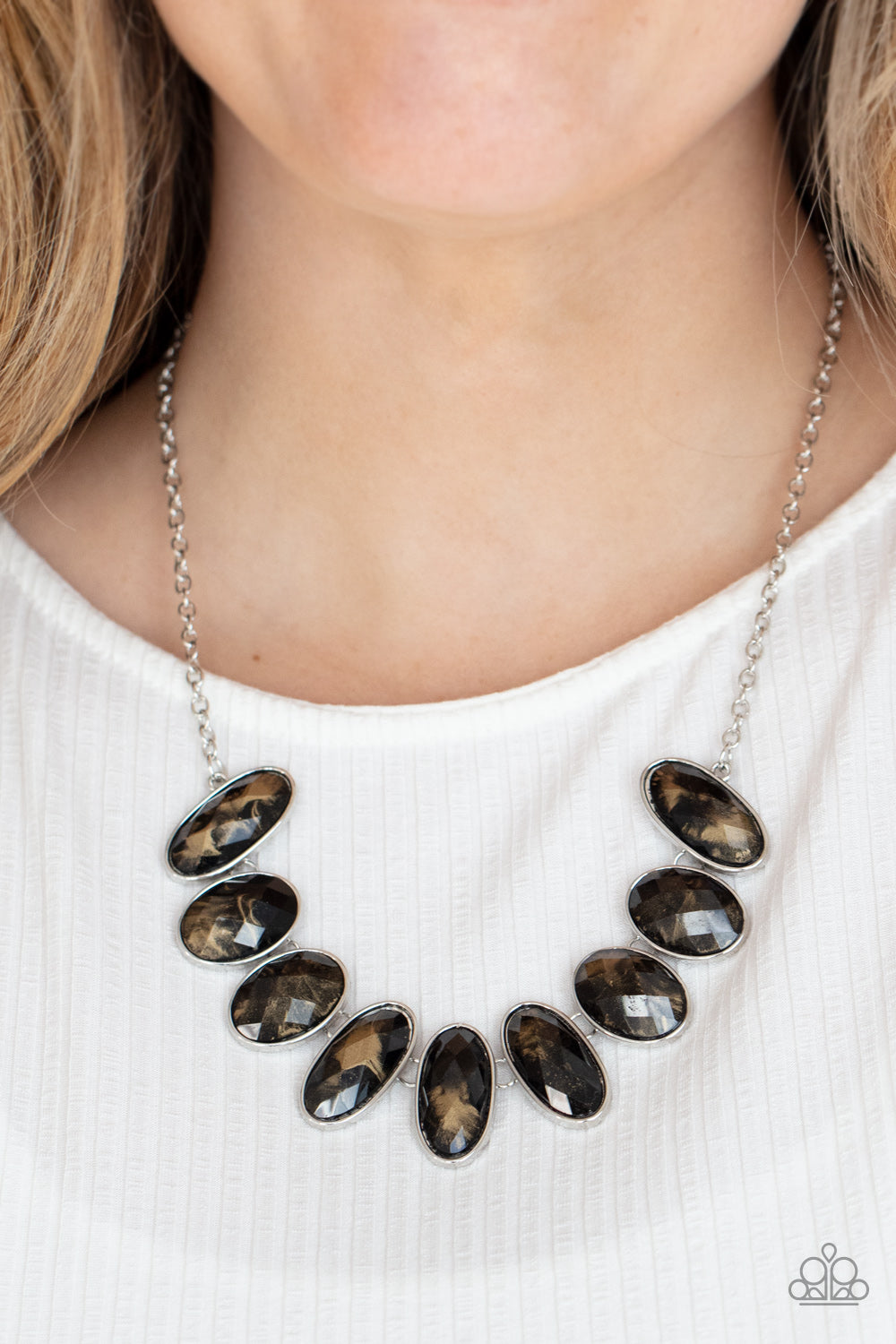 Generous glossy black gems, dusted in shimmery gold, lay in silver oval frames 