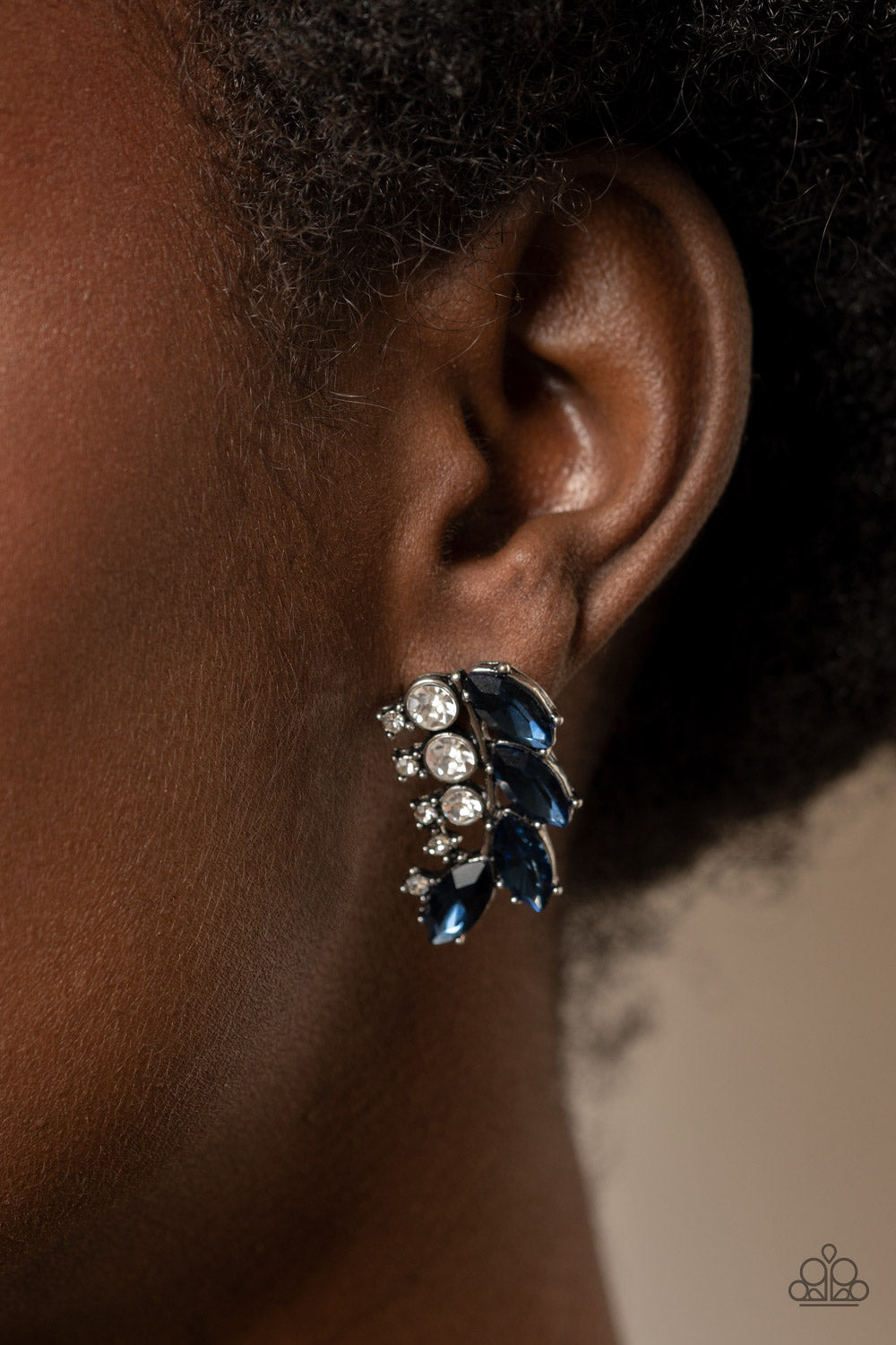 A frond of dazzling blue marquise and round white rhinestones delicately curves below the ear