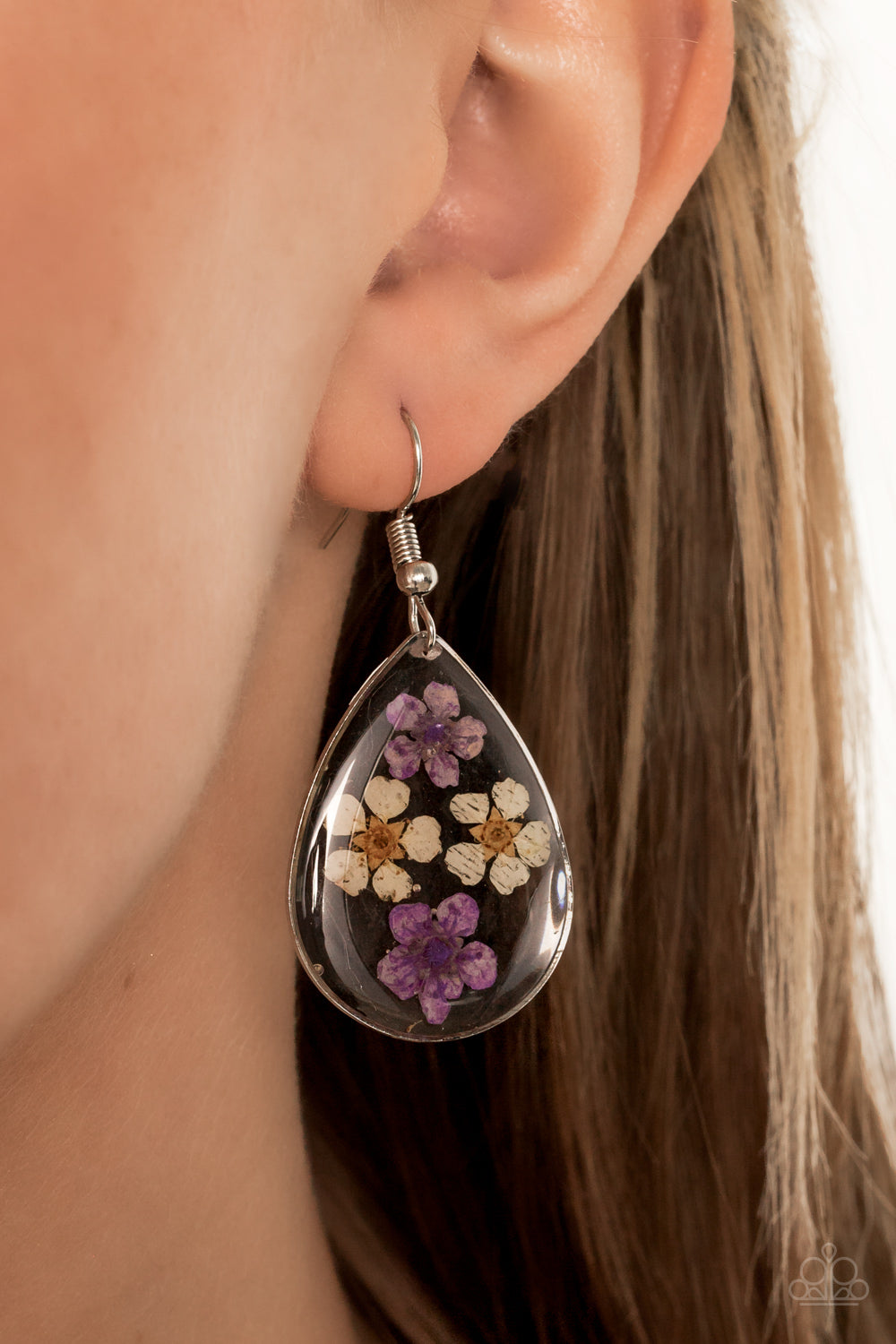 Dainty yellow and purple flowers are encased in a glassy teardrop, creating a whimsical frame.