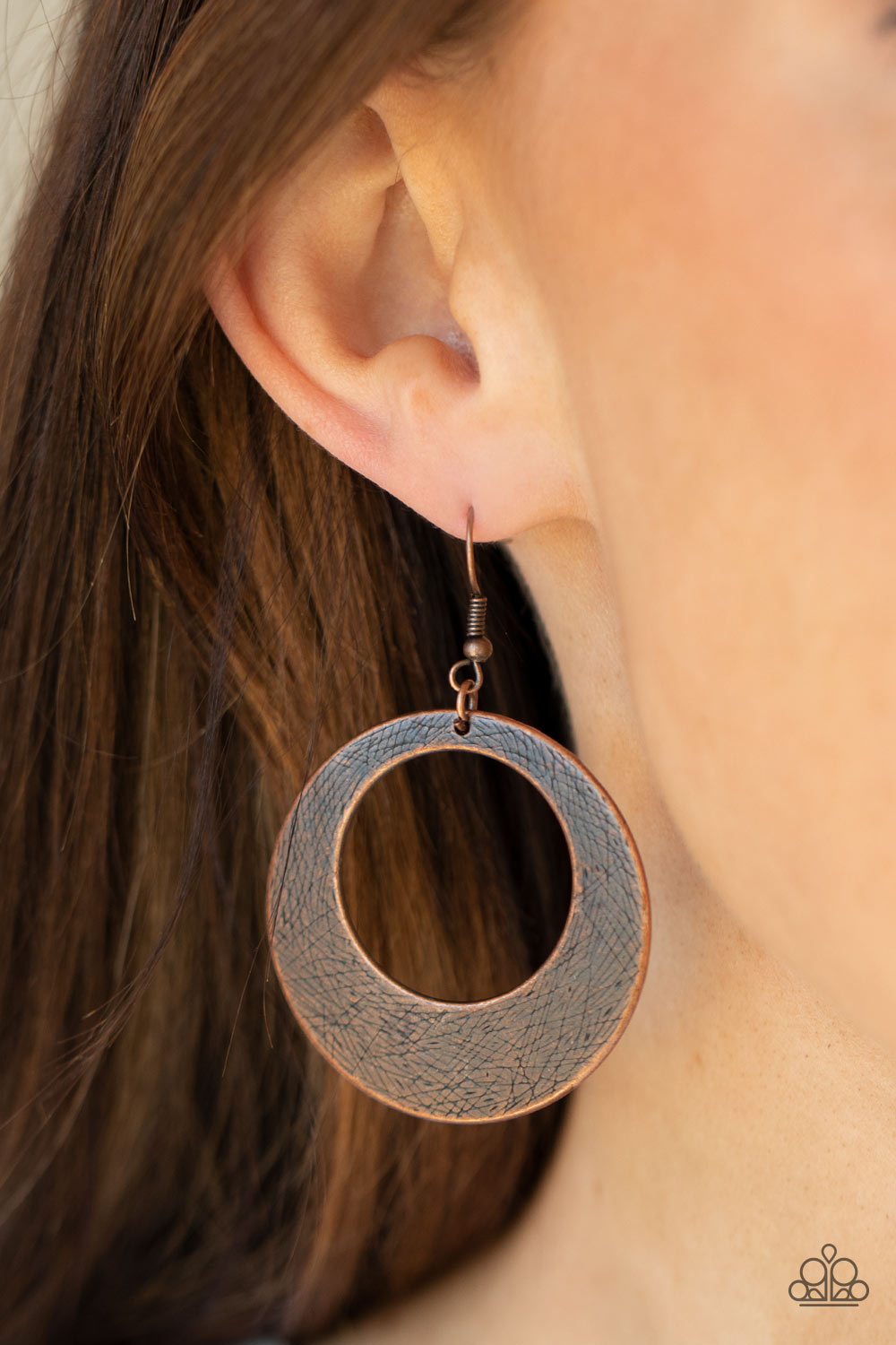 Brushed in an antiqued shimmer, a round copper frame is scratched in a gritty linear pattern for a rustic fashion