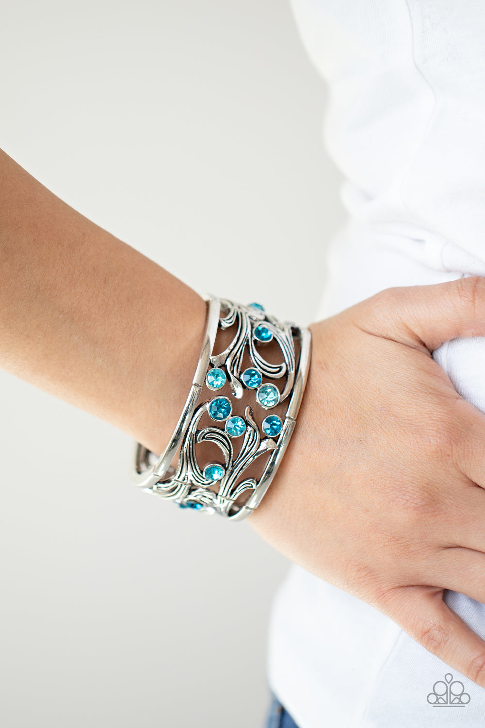 An ombre of blue rhinestones scatters across an airy floral frame among vine-like filigree