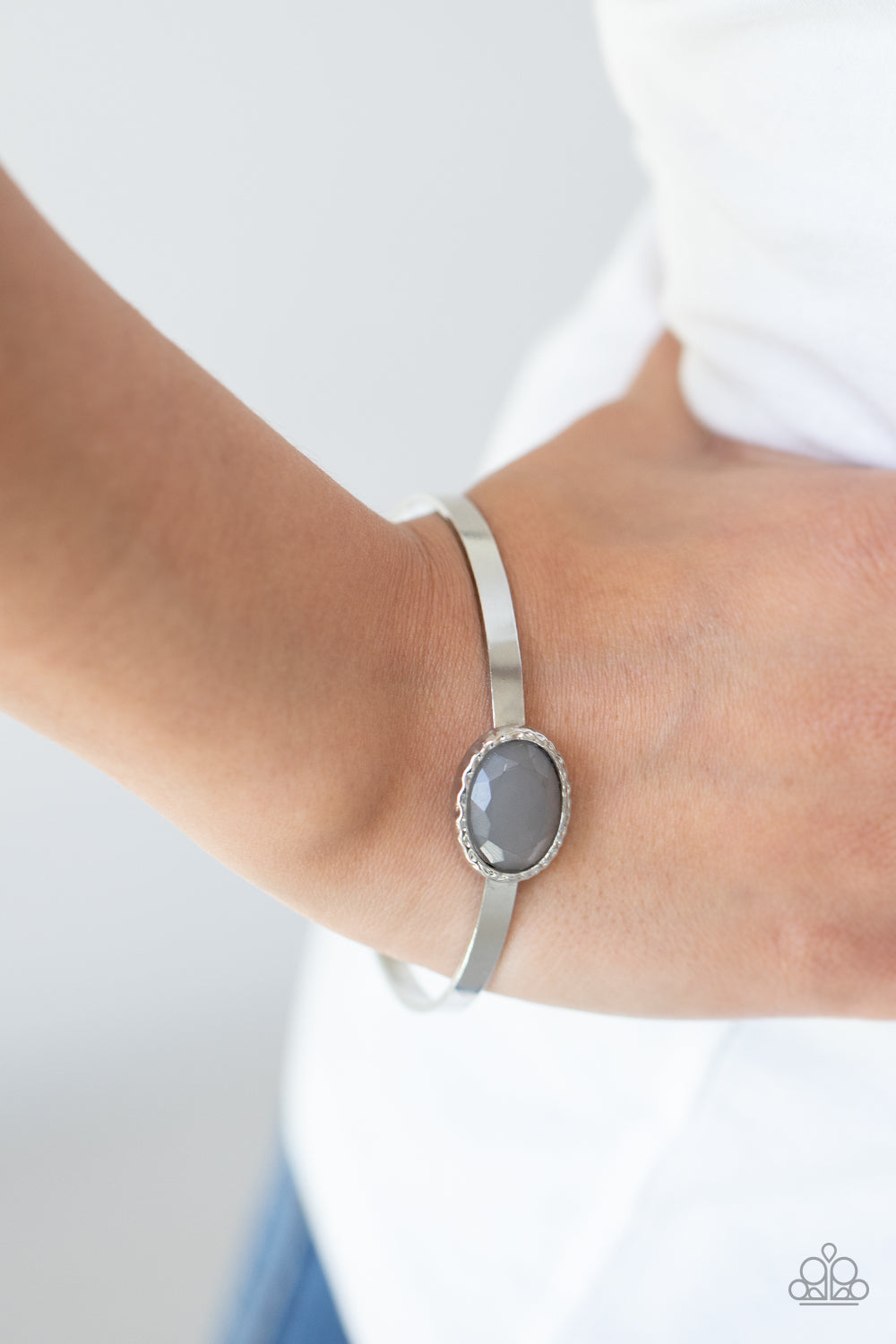 misty gray gem is pressed into the center of a hammered silver fitting atop a thick silver bangle