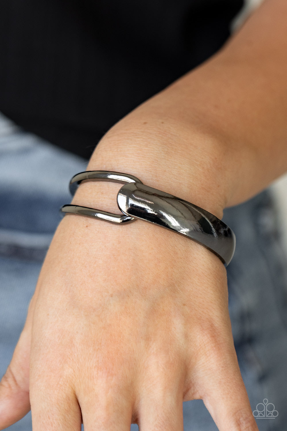 flat gunmetal bar and airy gunmetal frame delicately overlap around the wrist, creating an oversized cuff-like bangle