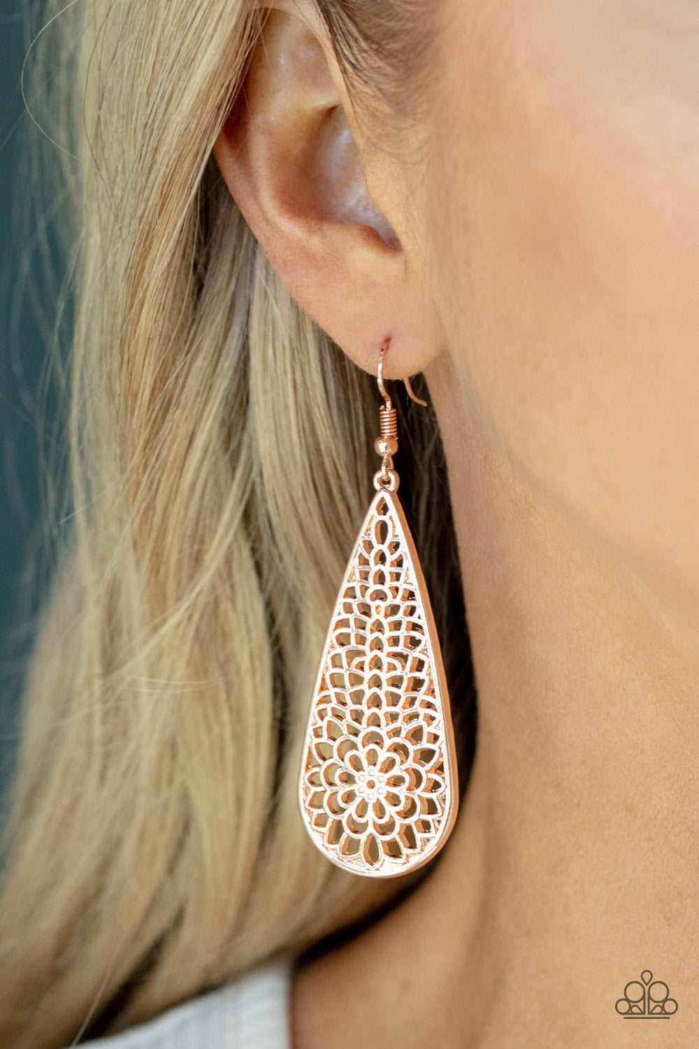 A mesmerizing explosion of shiny rose gold filigree petals bursts inside an oversized teardrop frame